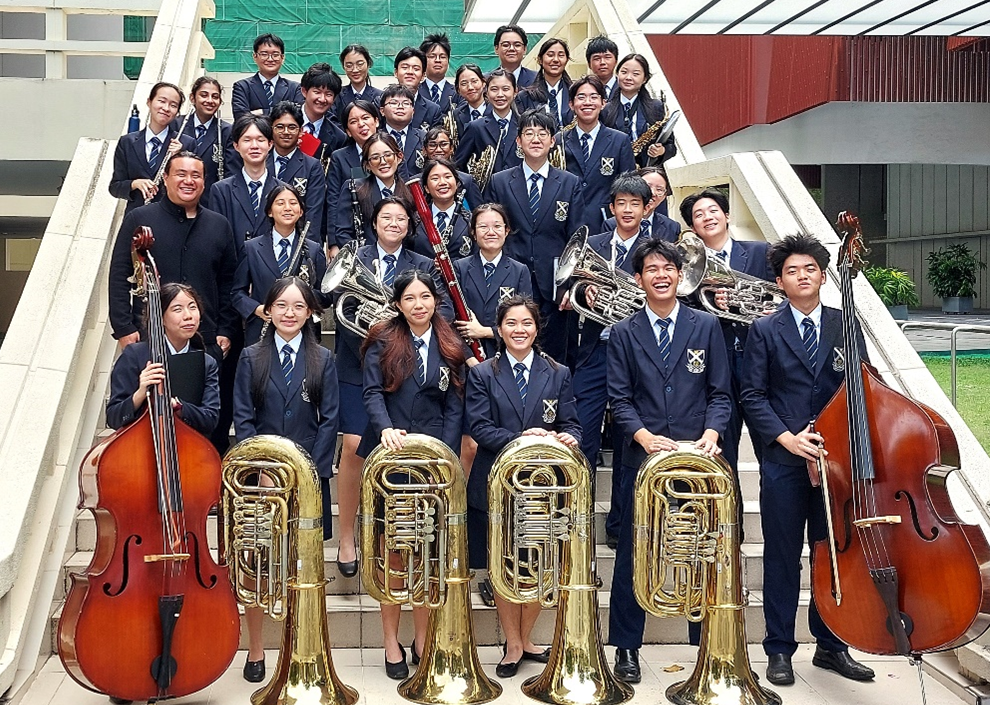 The Concert Band posing for a group shot with their instruments at the Singapore Conference Hall after the Singapore Youth Festival Showcase in 2025.