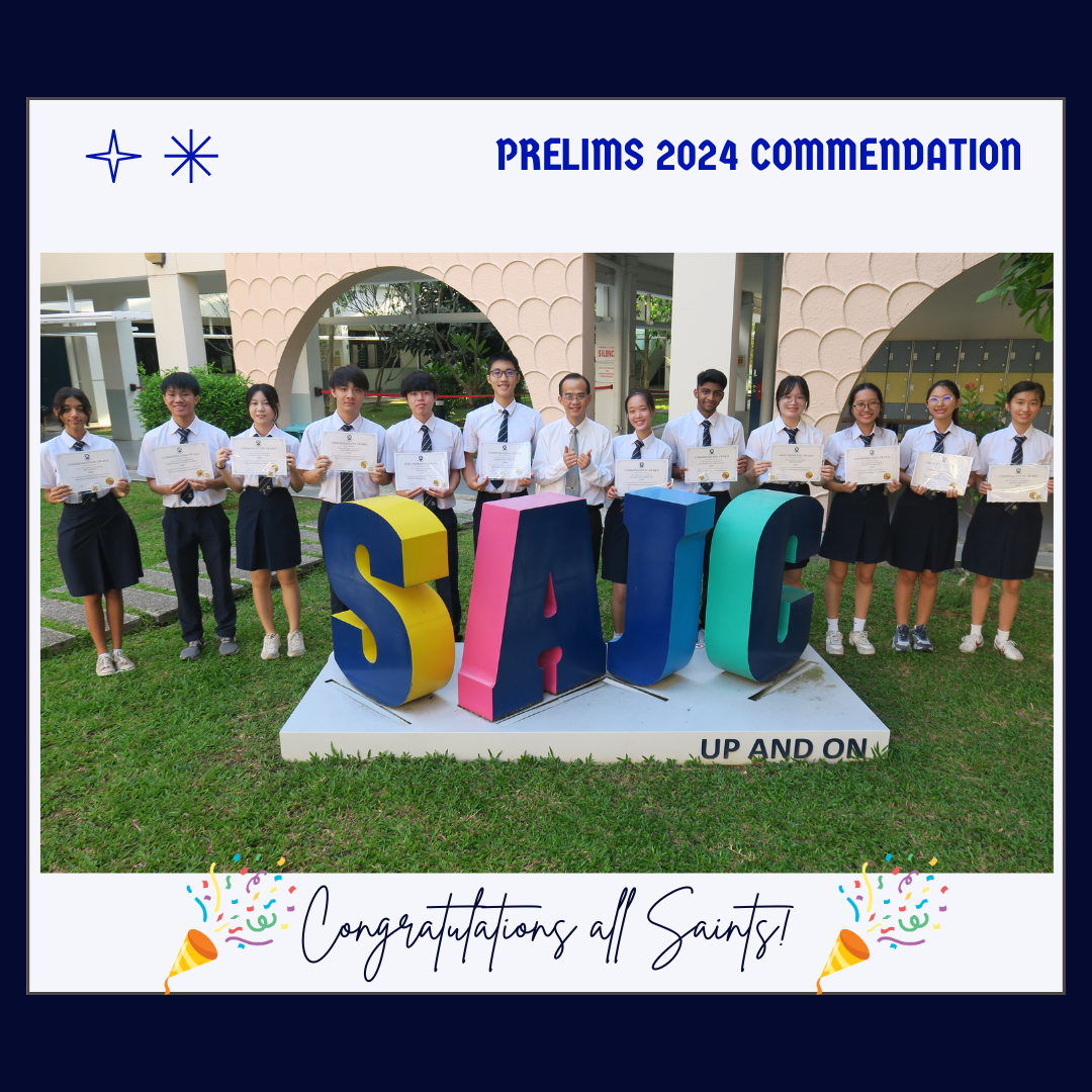 Students in uniforms holding certificates stand behind a colorful SAJC sign for Prelims 2024 Commendation.