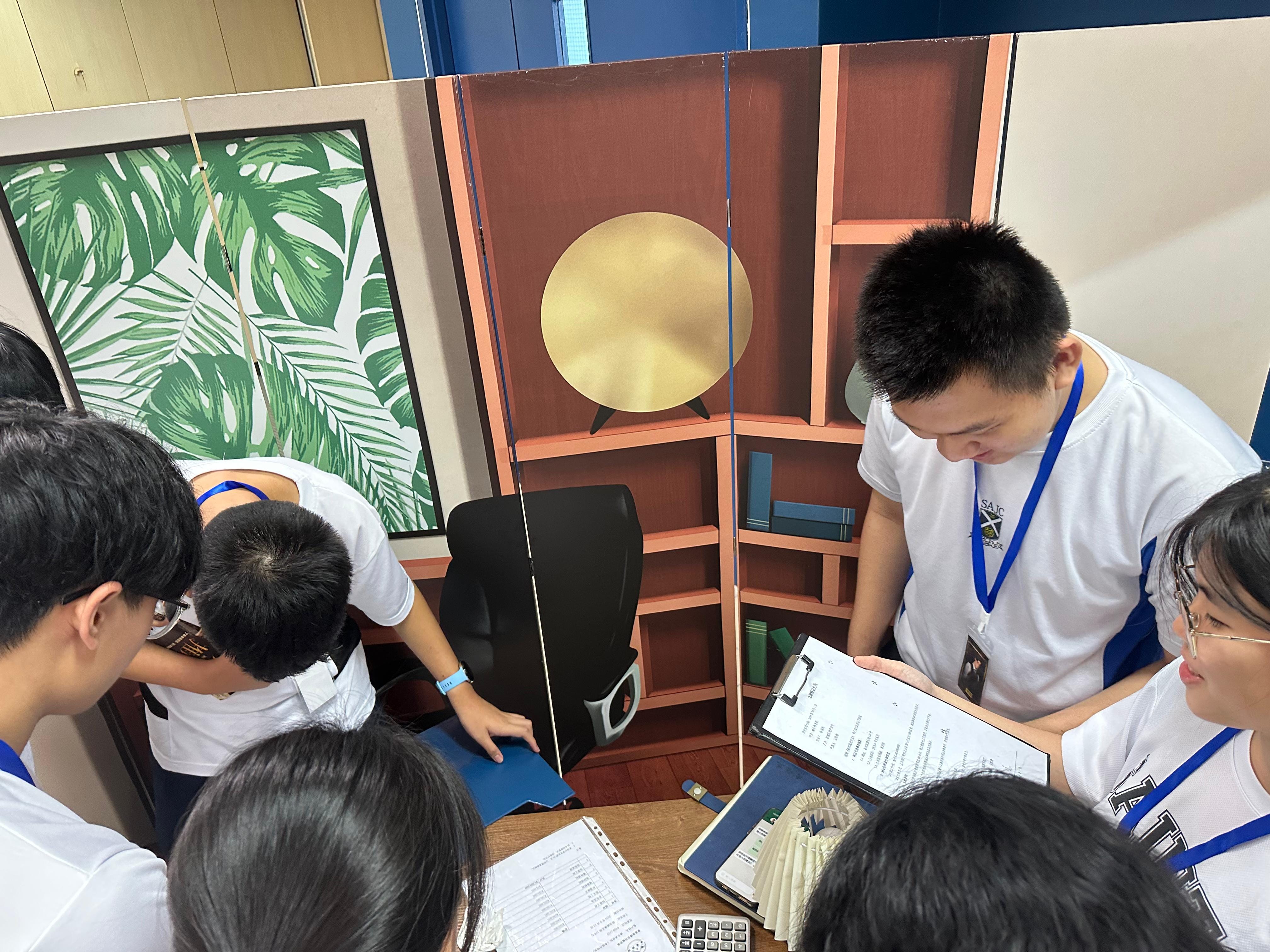 Students gathered around a table looking through some documents with a designed backdrop.