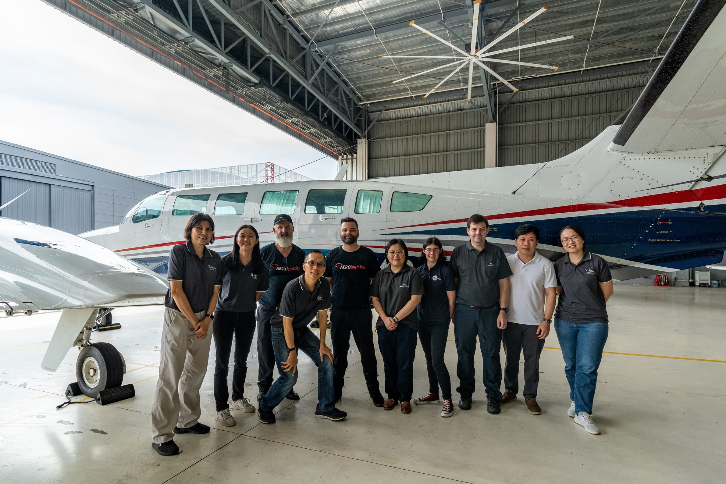 Group of SLA staff posing in front of an aircraft
