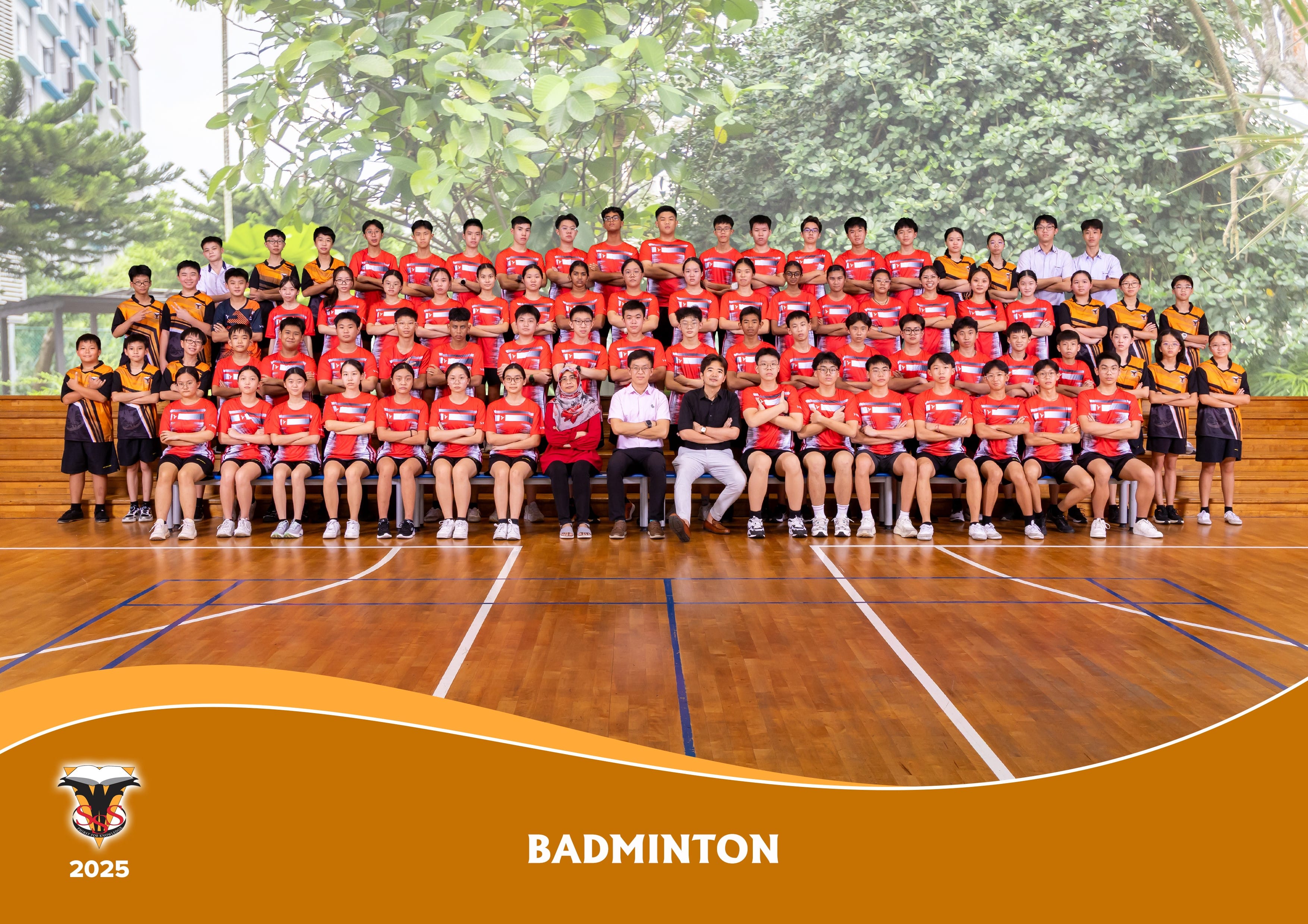 School badminton team group photo with students in red attire posing in school hall.