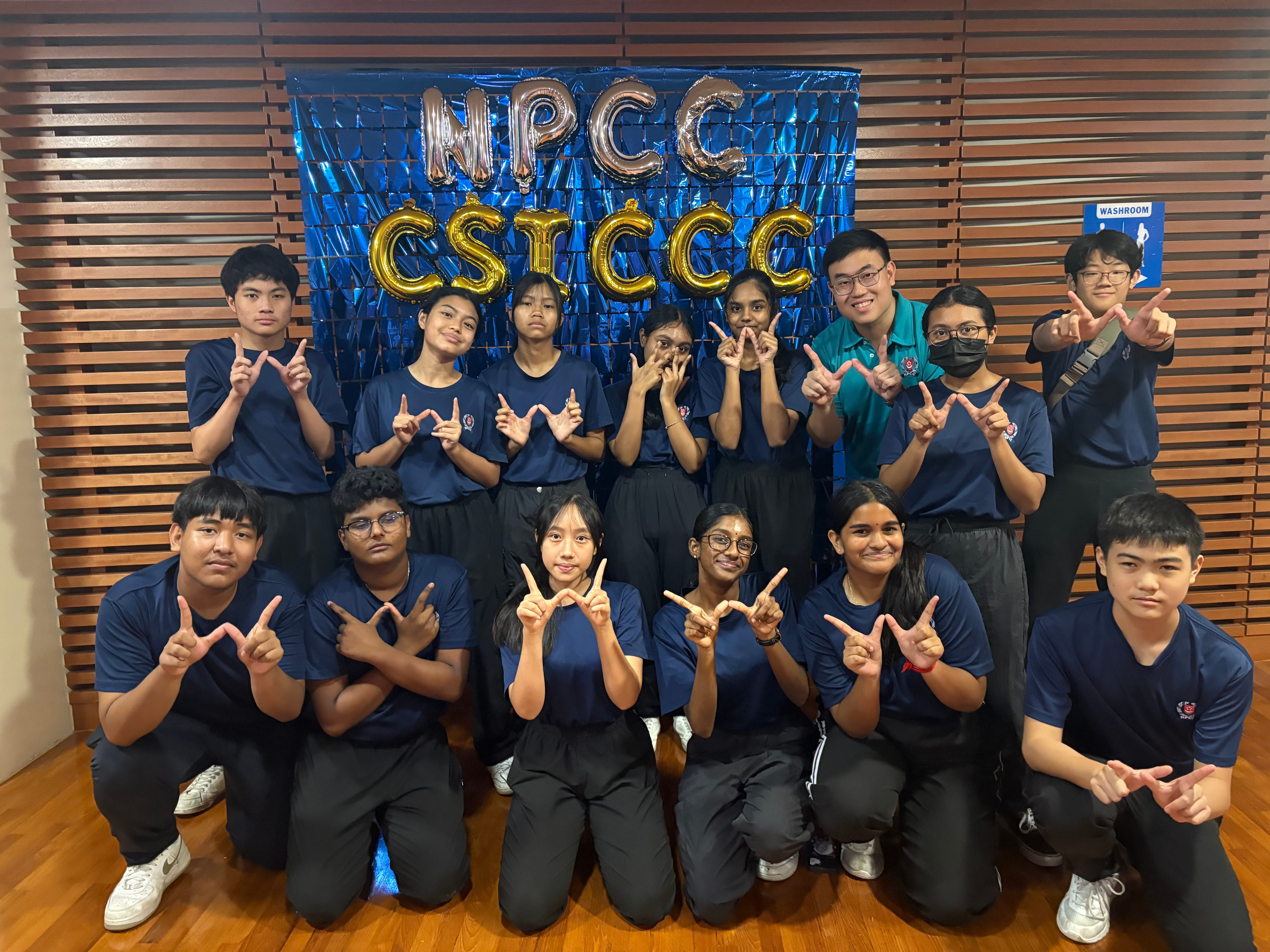 A group of young people in navy blue uniforms and berets pose outdoors holding a National Police Corps flag.