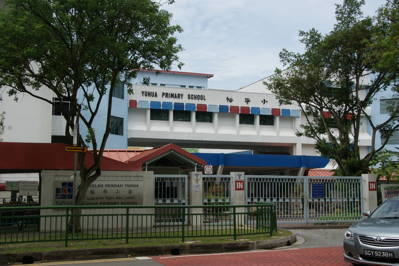 Yuhua Primary School building with white facade, red and blue accents, gated entrance, and trees in front.