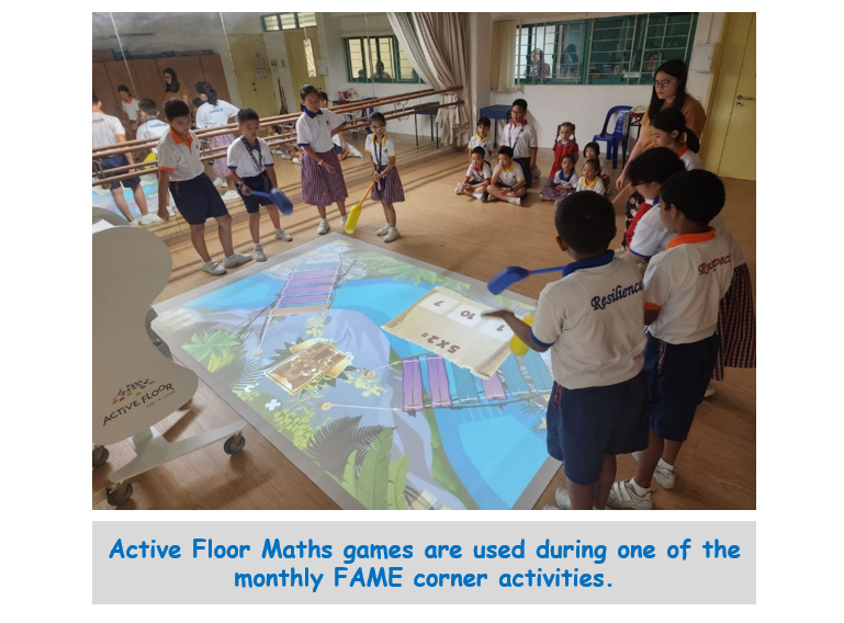 Students in uniforms play an interactive math game projected on the floor using paddles in a school hall.