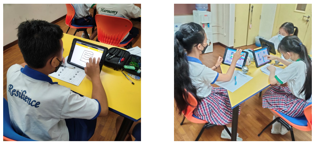 Students in school uniforms and masks sit at yellow desks using tablets in a classroom setting.