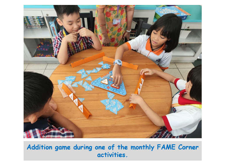 Three children sit around a round wooden table playing a board game with blue triangle pieces and orange dividers.