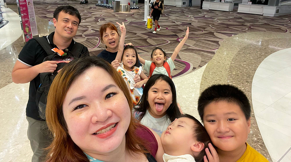 Family taking a group selfie together at an airport terminal