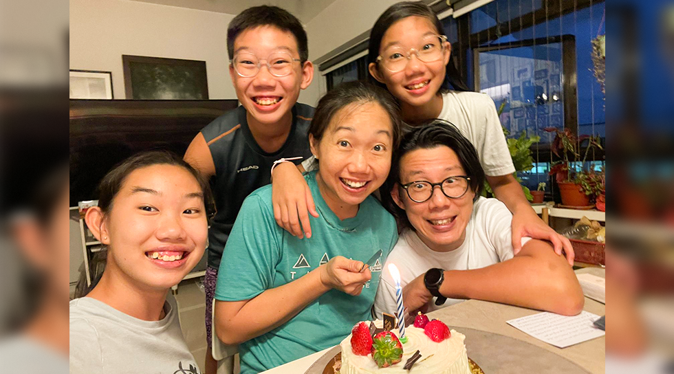 Family gathered around a birthday cake, smiling together at home