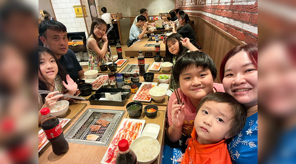 Family dining together at a restaurant with barbecue grills and shared dishes on the table