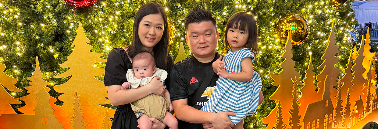 Family of four posing in front of illuminated Christmas decorations and festive lights