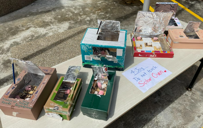 The third image (S5) shows student-made solar ovens constructed from cardboard boxes, aluminium foil, and other materials, displayed on a table outdoors. A handwritten sign reads "1 Day. Do not touch. Solar Oven" with a heart. This looks like a hands-on design challenge activity.