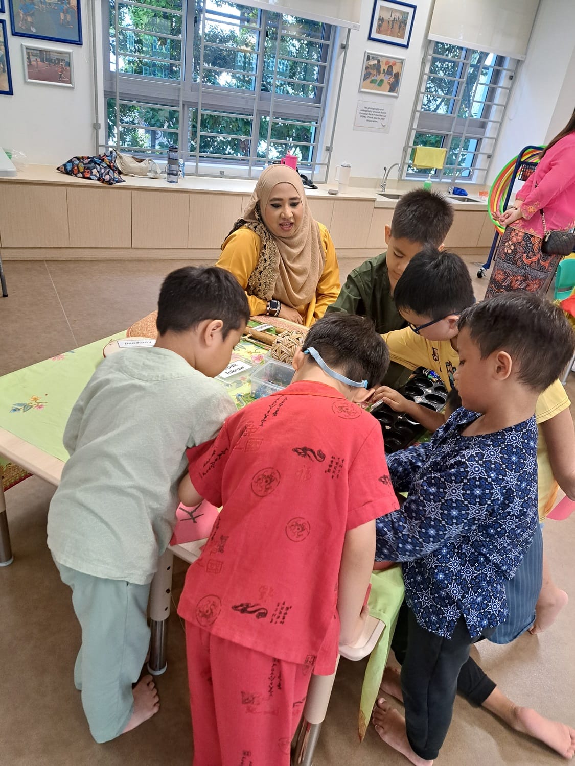 Children having a game of Congkak with our parent volunteer.