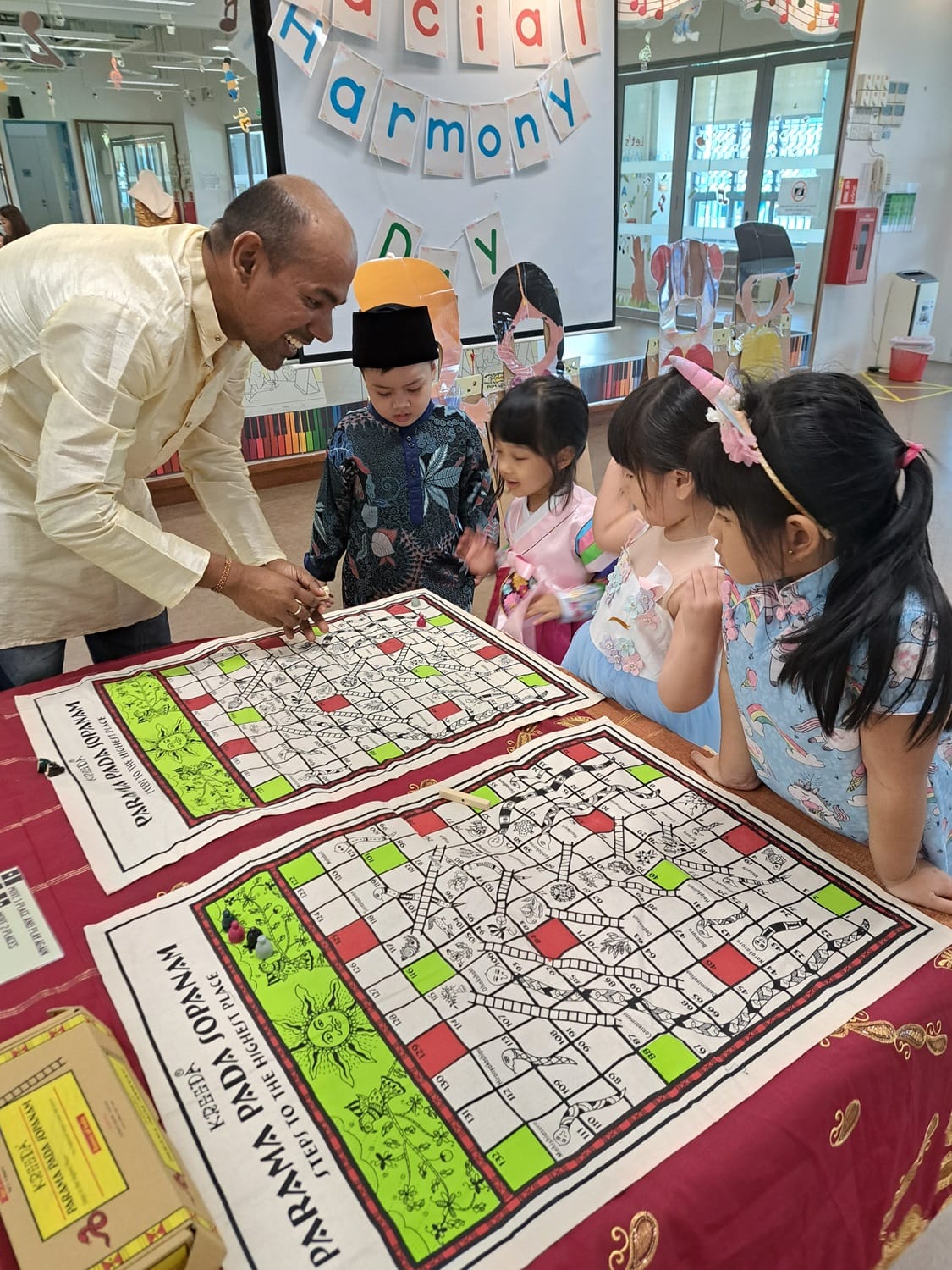 Parent explaining the rules on ‘Parama Pada Sopanam’, a traditional Indian version of the popular game of Snakes and Ladders.