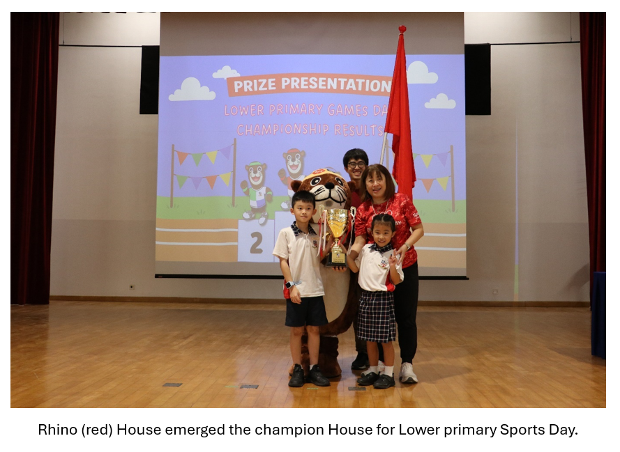 Two students pose with a trophy and red flag in front of a Prize Presentation slideshow on stage with Principal and teacher-in-charge.