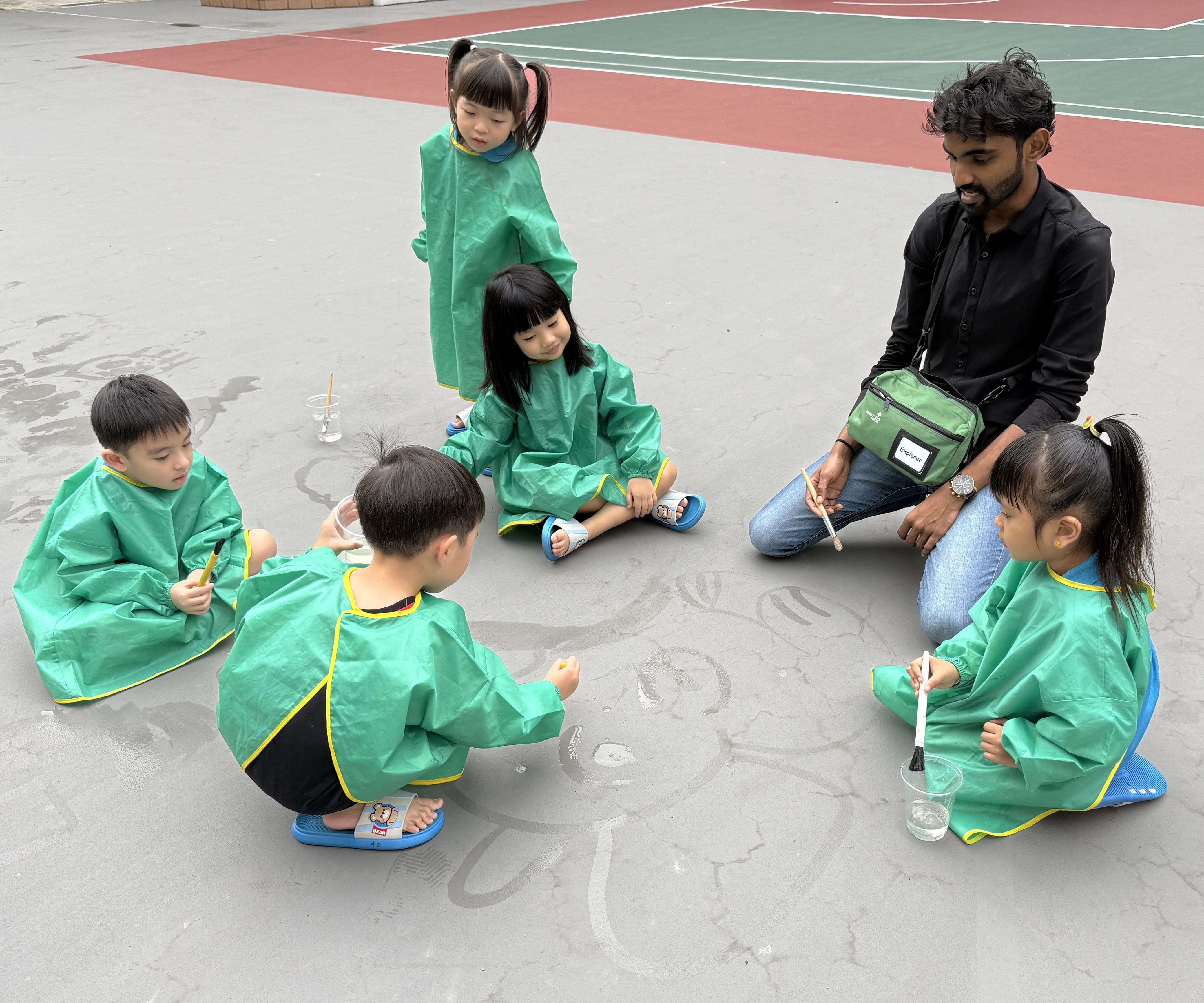 Children drawing at the basketball court with water and brush