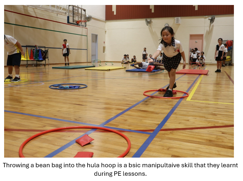Young girl in school uniform tossing a bean bag toward a red hula hoop on a gymnasium floor.