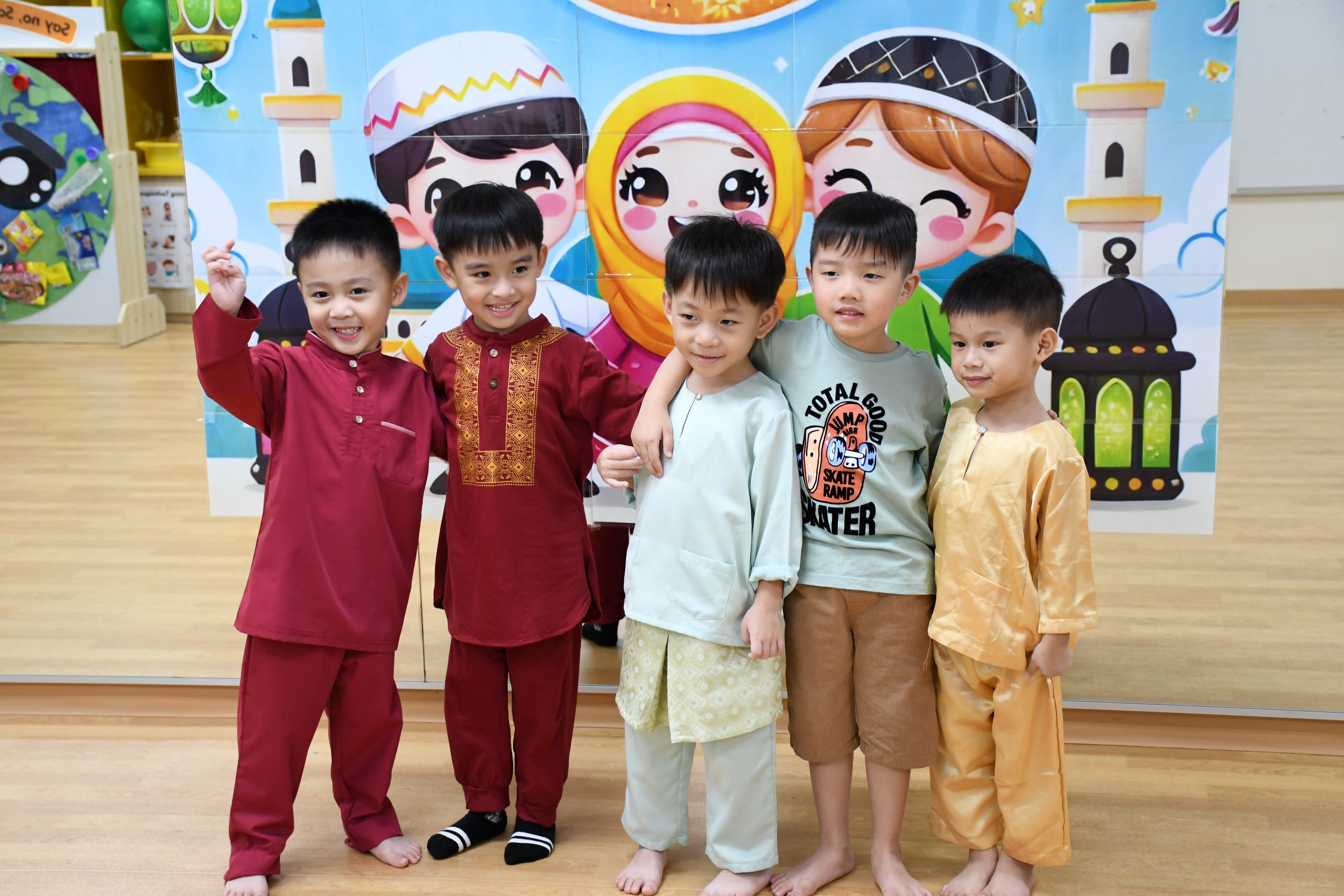 Five young boys posing with arms around each other before a colorful cartoon mosque-themed backdrop.