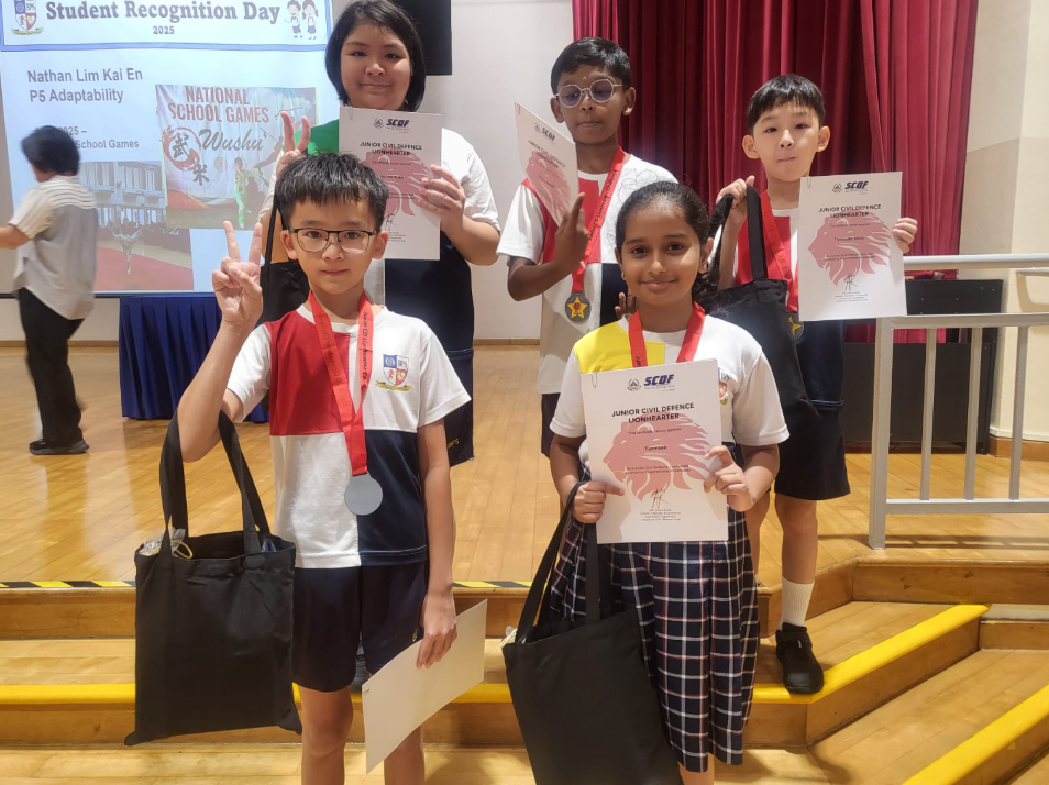 Five students holding SCDF Junior Civil Defence Lionhearter certificates and tote bags at a Student Recognition Day event.