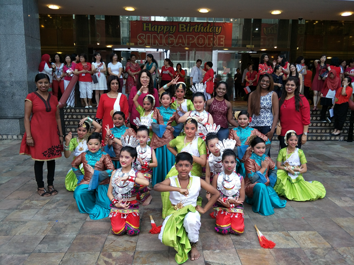 Students dressed in vibrant traditional costumes performing an Indian dance.