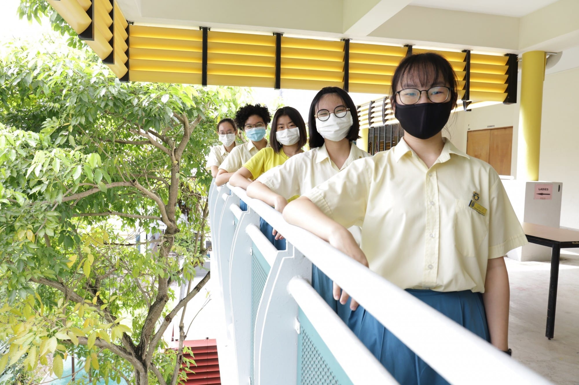 Student in mask standing along railing