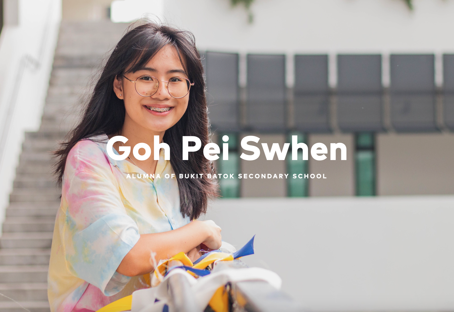 Smiling young woman with glasses and braces in a tie-dye shirt, labeled Goh Pei Swhen, alumna of Bukit Batok Secondary School.