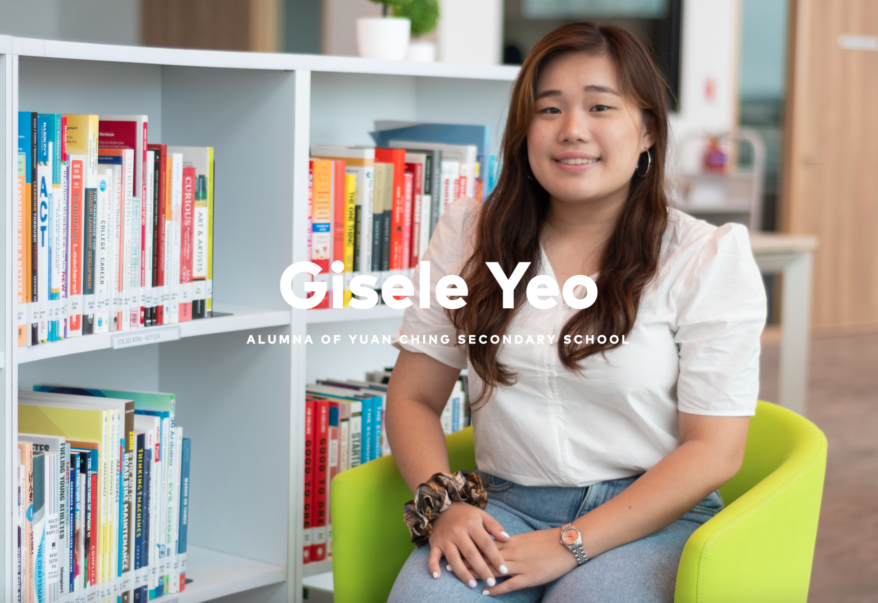 Young woman named Gisele Yeo smiling in a library, seated on a green chair beside colorful bookshelves.
