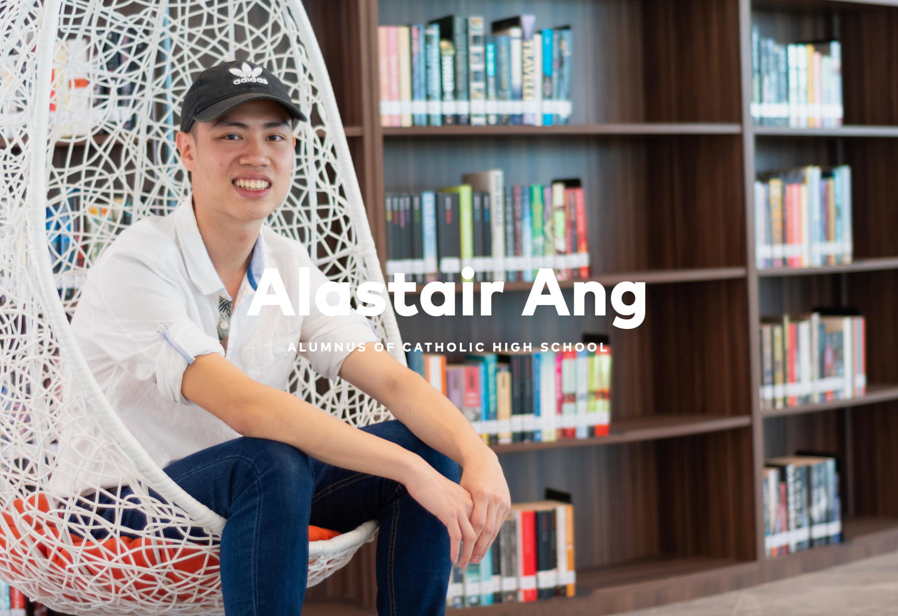 Smiling man in a black cap sits in a white hanging chair by bookshelves; text reads Alastair Ang.