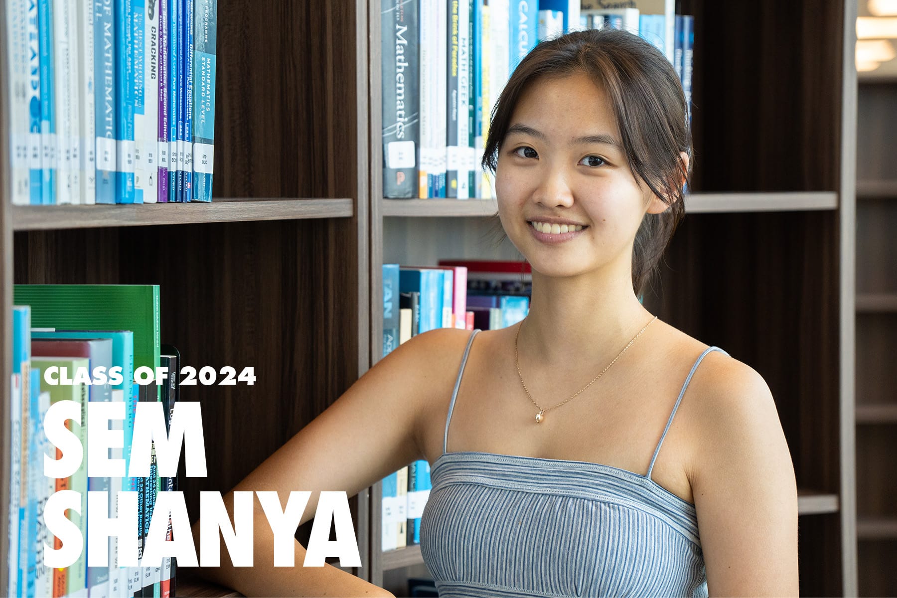 A smiling young woman in a gray top stands by bookshelves, with text reading Class of 2024 Sem Shanya.