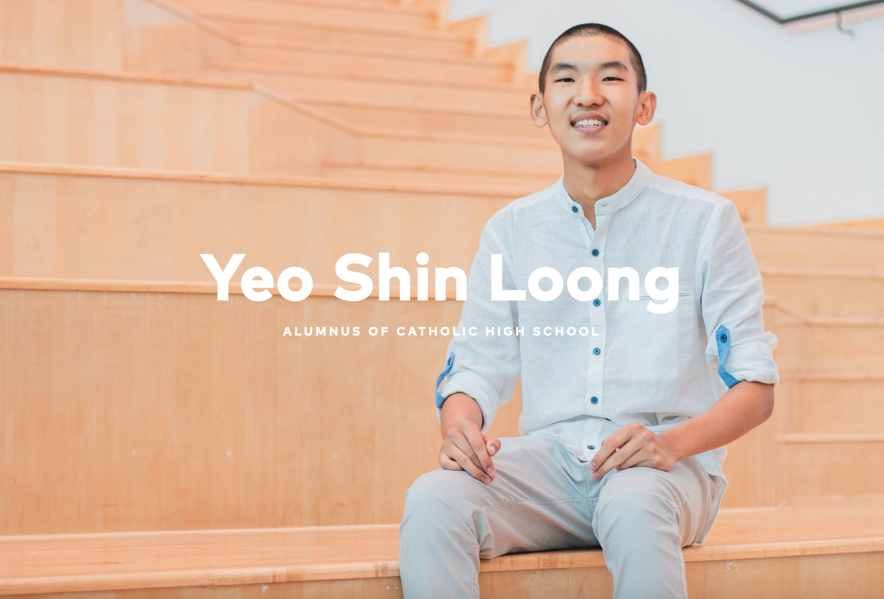 Yeo Shin Loong, alumnus of Catholic High School, smiling young man sitting on wooden stairs in a light blue shirt.