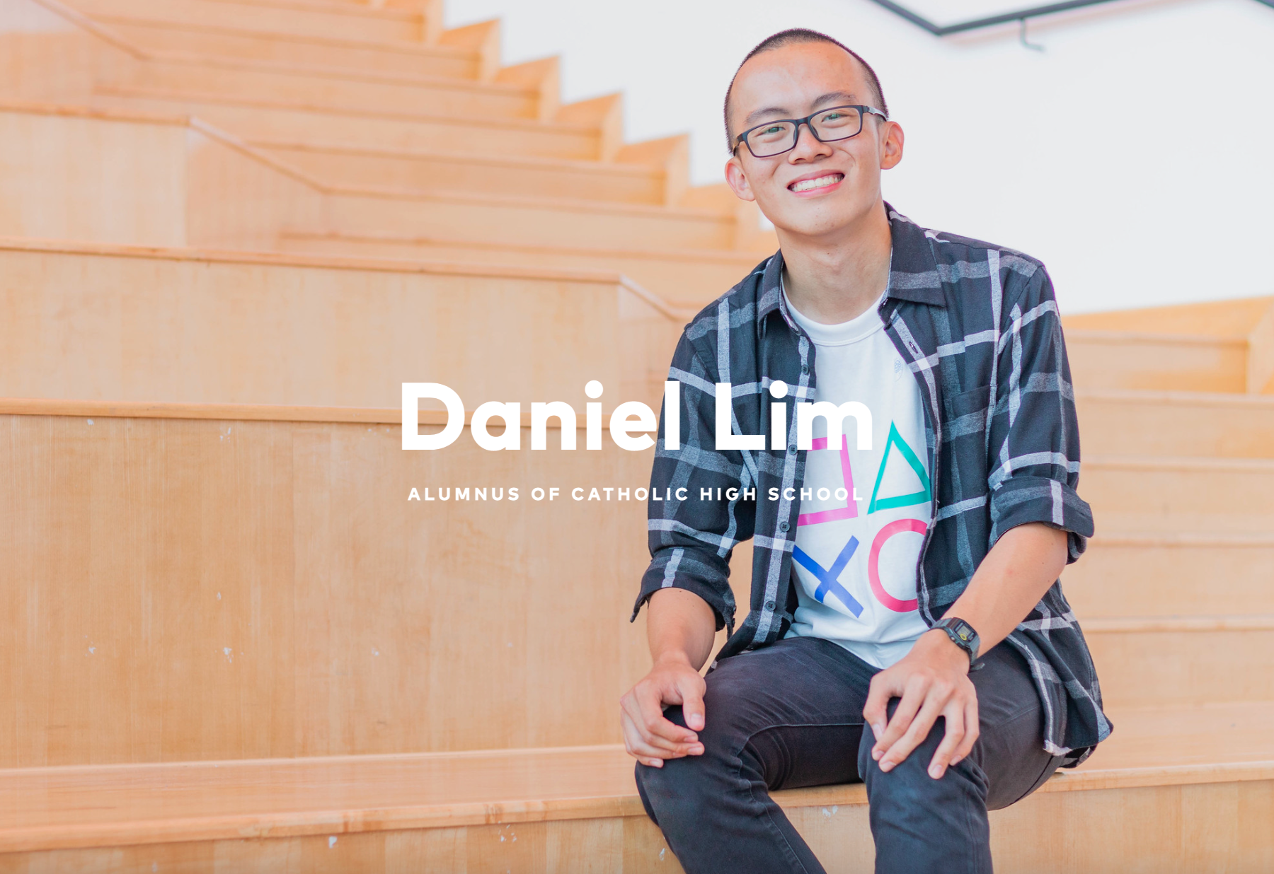 Daniel Lim, alumnus of Catholic High School, smiling young man with glasses sitting on wooden stairs.