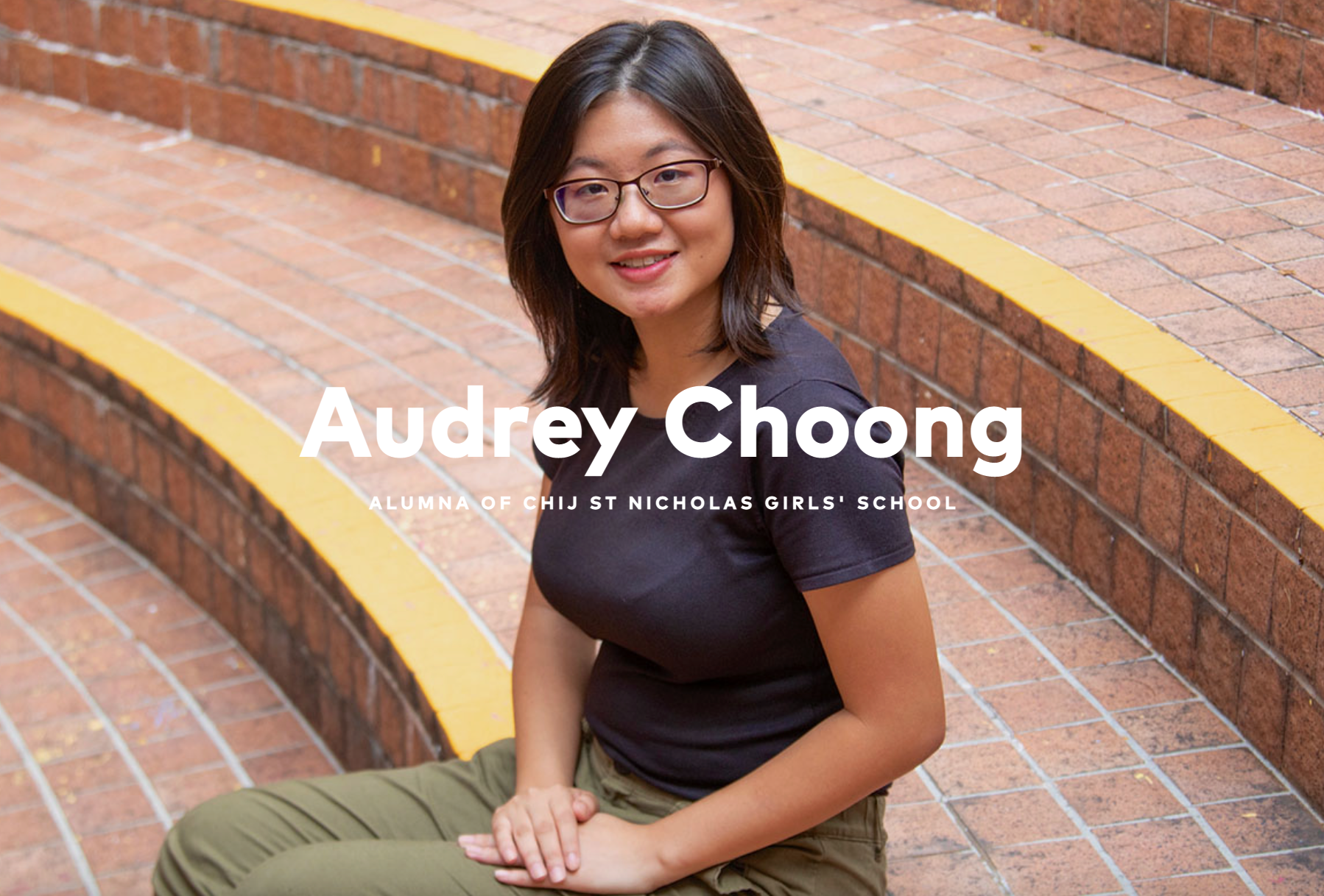 Audrey Choong, alumna of CHIJ St Nicholas Girls' School, smiling and seated on brick steps.
