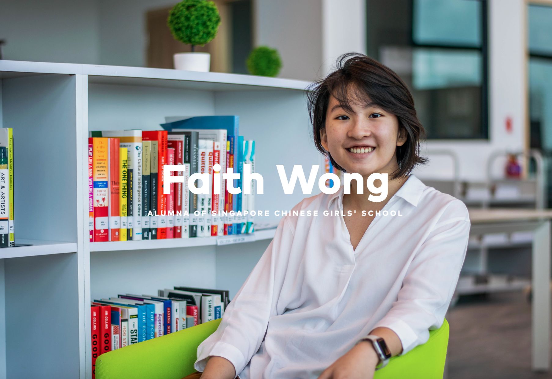 Faith Wong, alumna of Singapore Chinese Girls' School, smiling while seated in front of a colorful bookshelf.