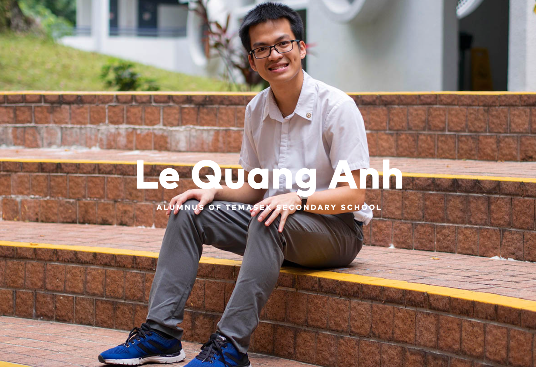 Young man named Le Quang Anh, alumnus of Temasek Secondary School, sitting on brick steps smiling.