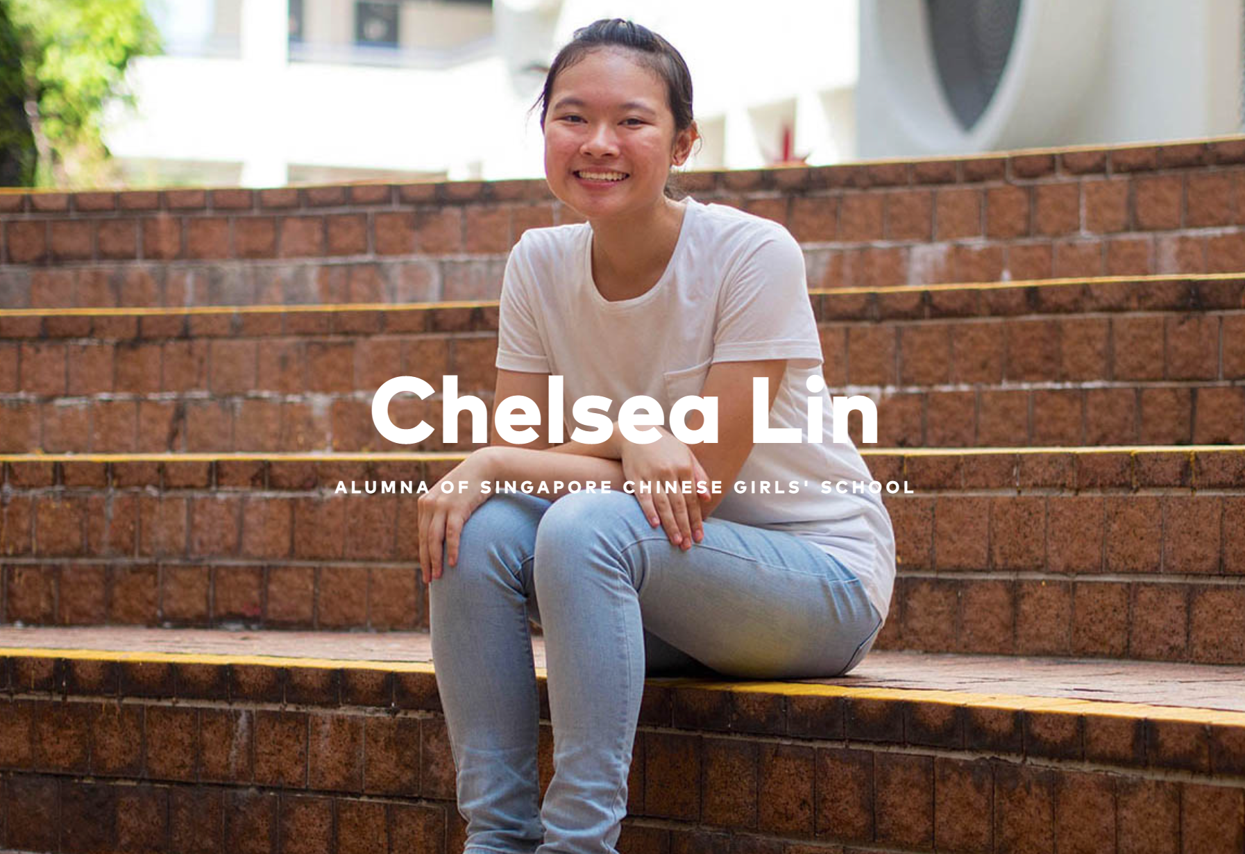 Chelsea Lin, alumna of Singapore Chinese Girls' School, smiling and sitting on brick steps outdoors.