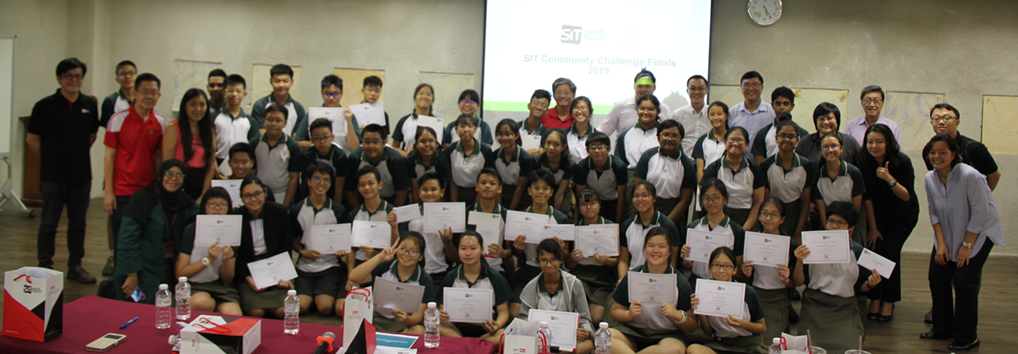 Large group of students and adults posing with certificates at SIT Community Challenge Finals event.