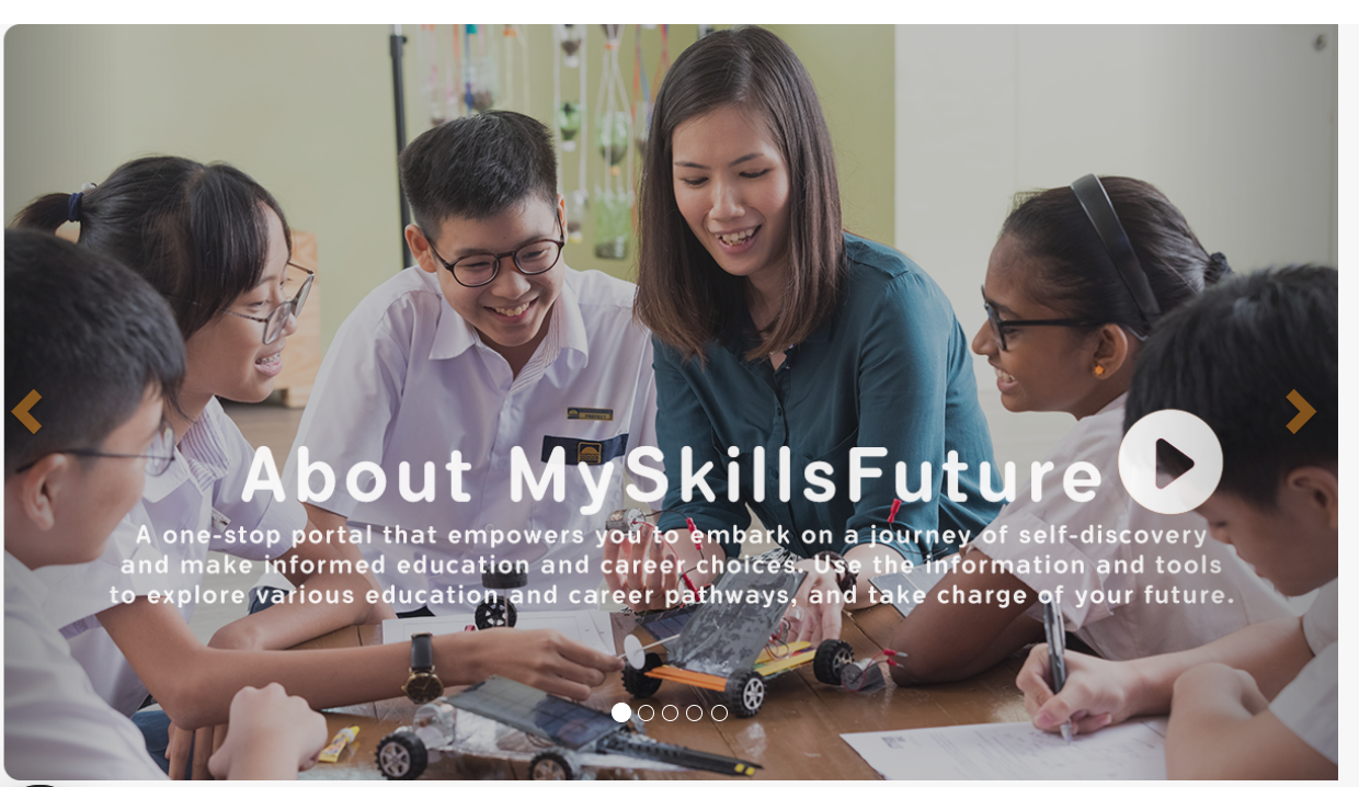 A teacher and students smile while working on a small model car at a table in a classroom.