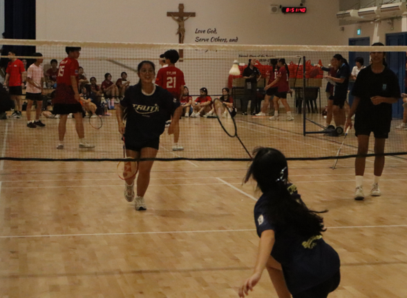 Students playing a volleyball match in the indoor sports hall during a Physical Education lesson.