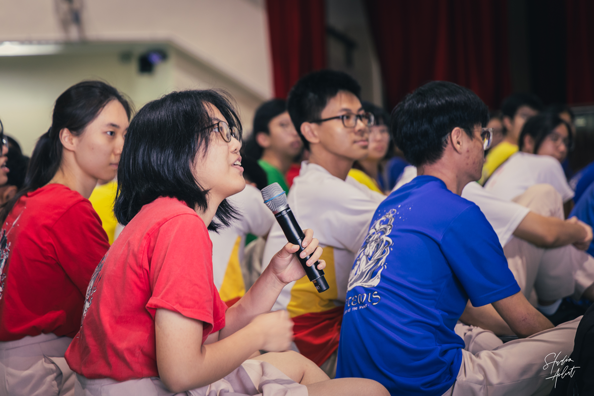 A C2 student speaking into the microphone to share ideas.