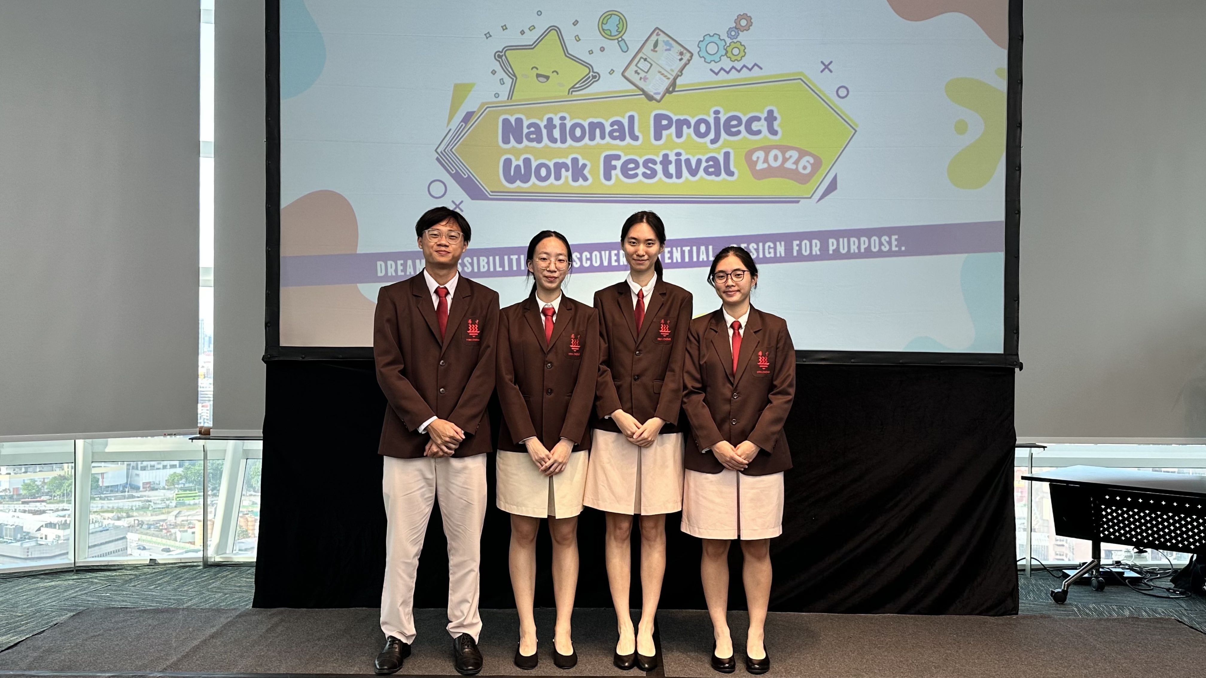 Four students in brown blazers and red ties stand before a National Project Work Festival 2026 screen.