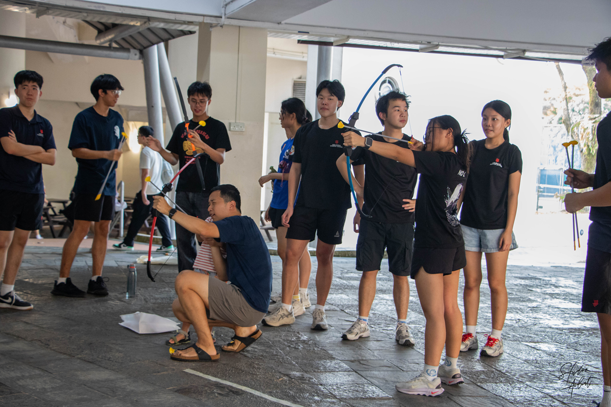 Students and visitors practicing archery with foam-tipped arrows at an indoor booth during the Mid-Autumn Festival campus celebration.