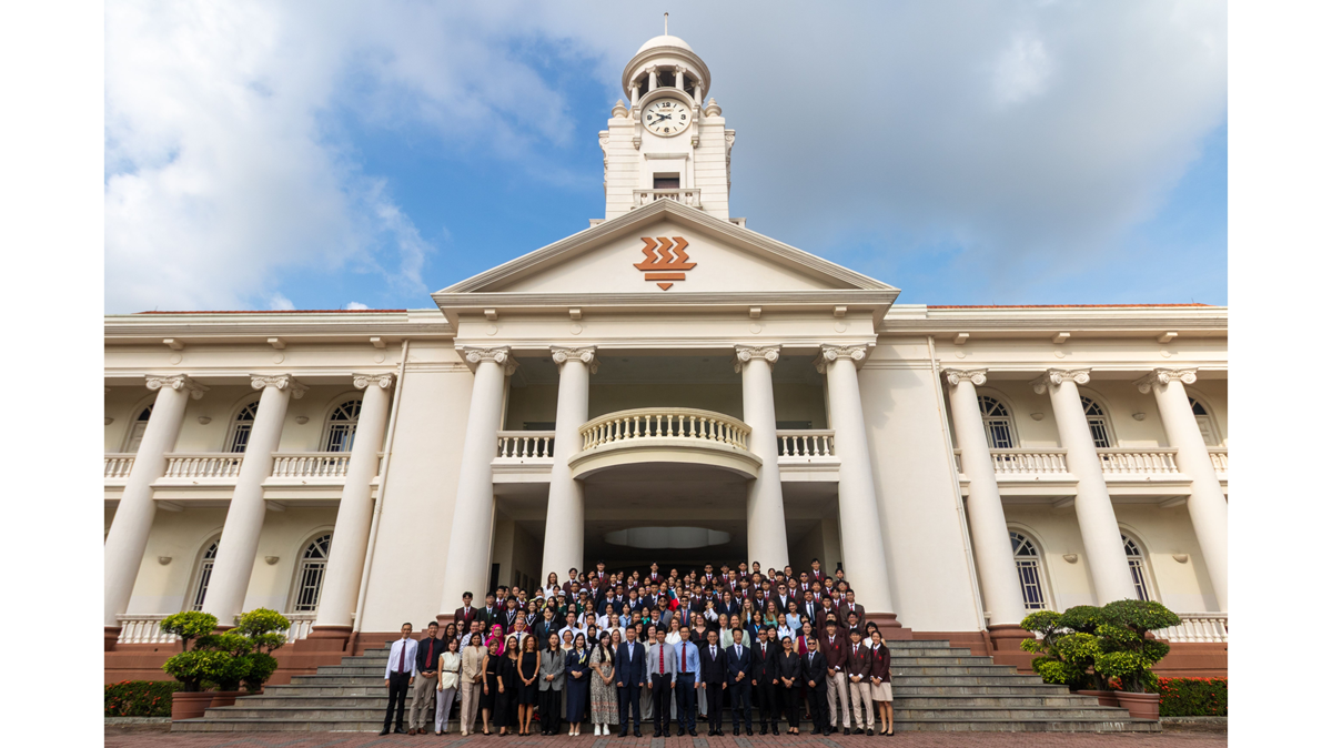 A large group of delegates and distinguished guests posing on the steps in front of the iconic Hwa Chong Institution clock tower building.