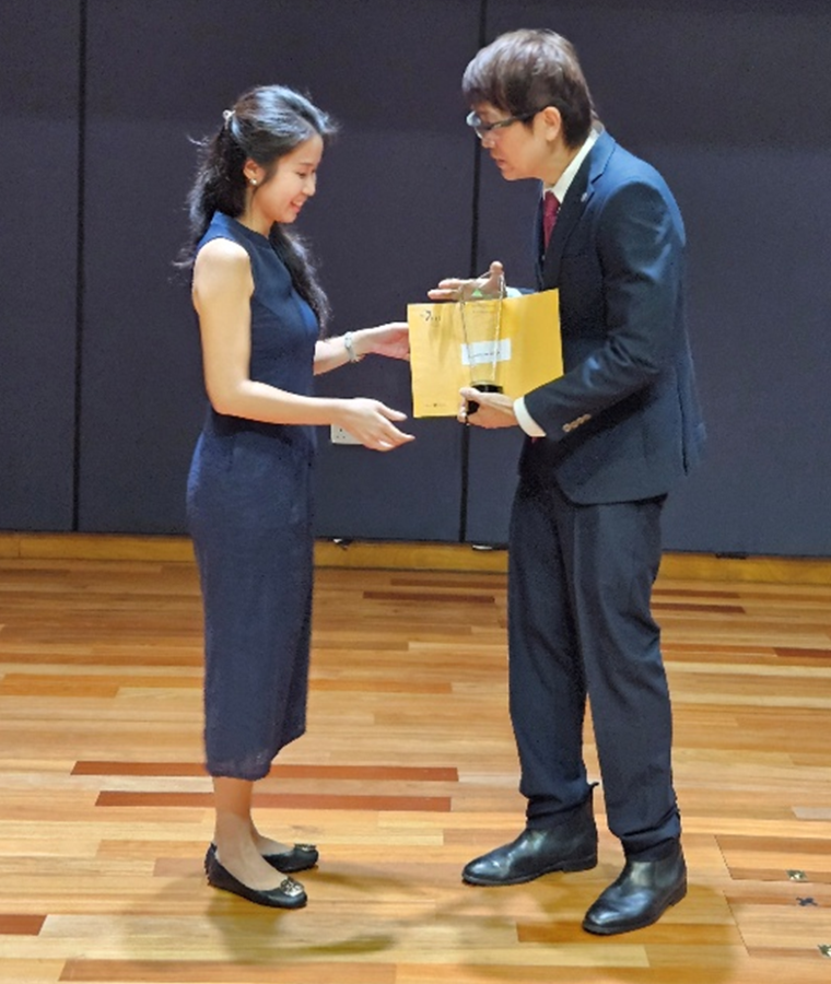 A woman receives a gift bag during an award ceremony.