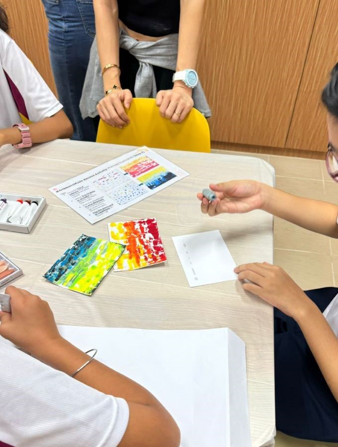 Students creating colourful artwork together at a table during a hands-on acrt activity
