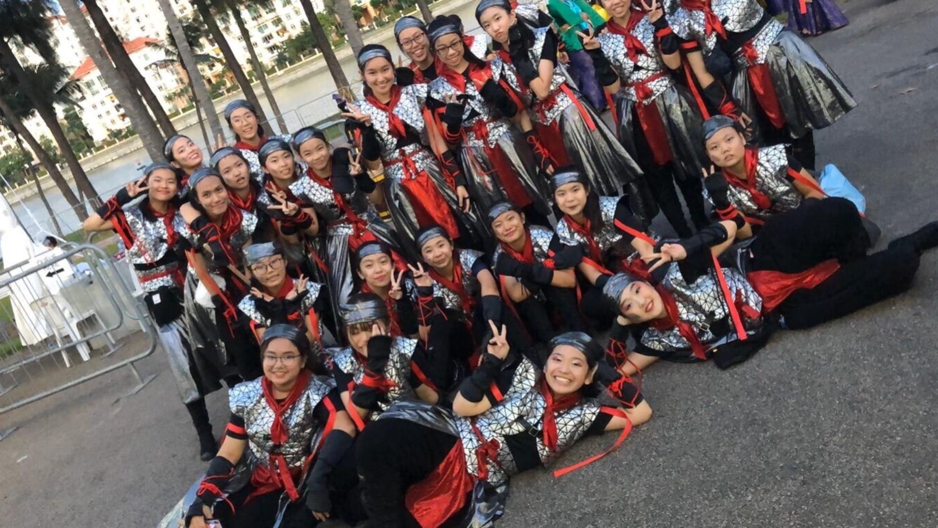 Chinese dance members in their performing outfit, posing for a picture outside of school