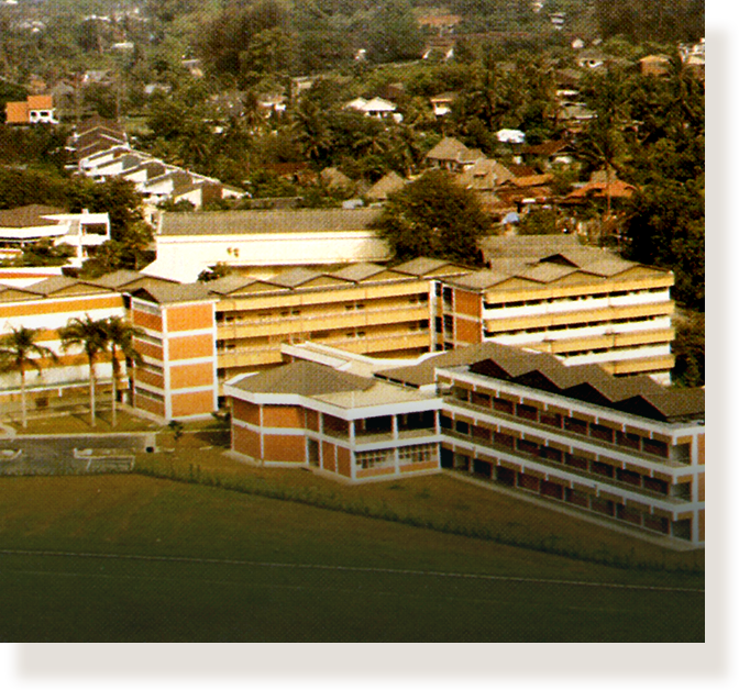 Aerial view of a large multi-story orange and white building complex surrounded by trees and houses.