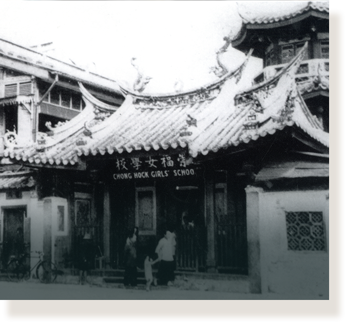 Black and white photo of Chong Hock Girls School with ornate curved Chinese roof and people standing at entrance.