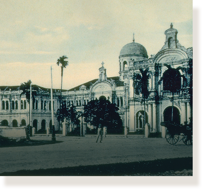 Old photo of a colonial building with a dome, arched facade, palm trees, and a horse-drawn carriage nearby.