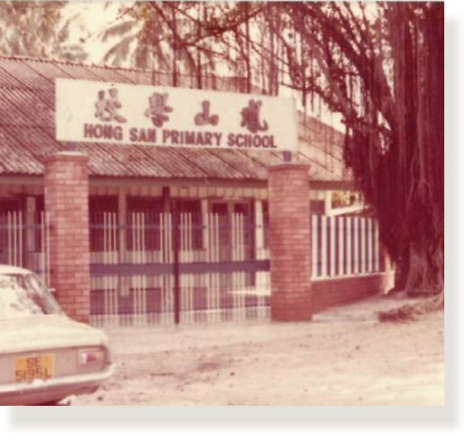 Vintage photo of Hong San Primary School entrance with brick pillars, metal gates, Chinese characters, and a parked car nearby.