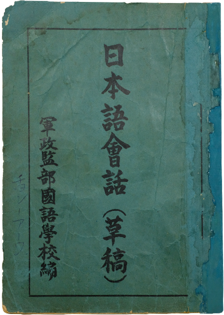 Worn green cover of an old Japanese book with black kanji characters and a blue spine.