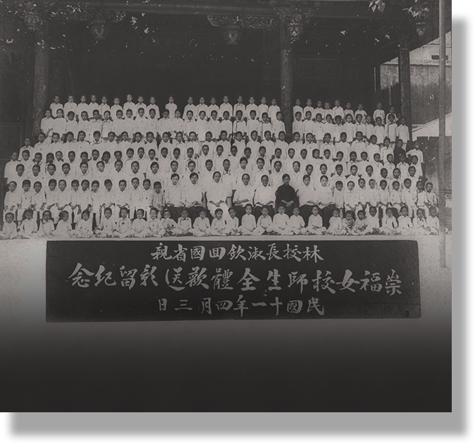 Old black and white group photo of many people in white clothing with a Chinese text sign in front.